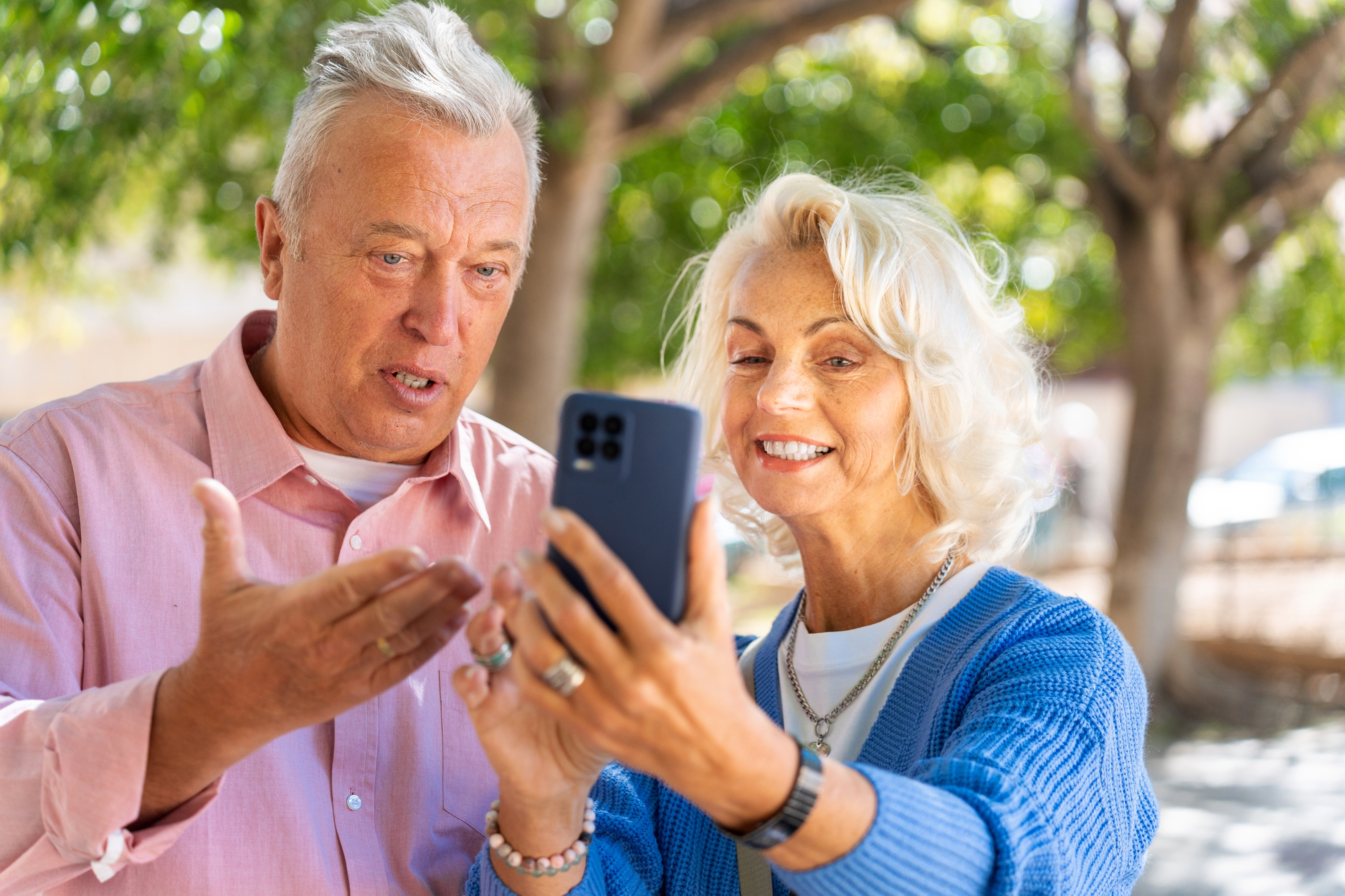 Älterer Mann und Frau sprechen und schauen in ein Smartphone