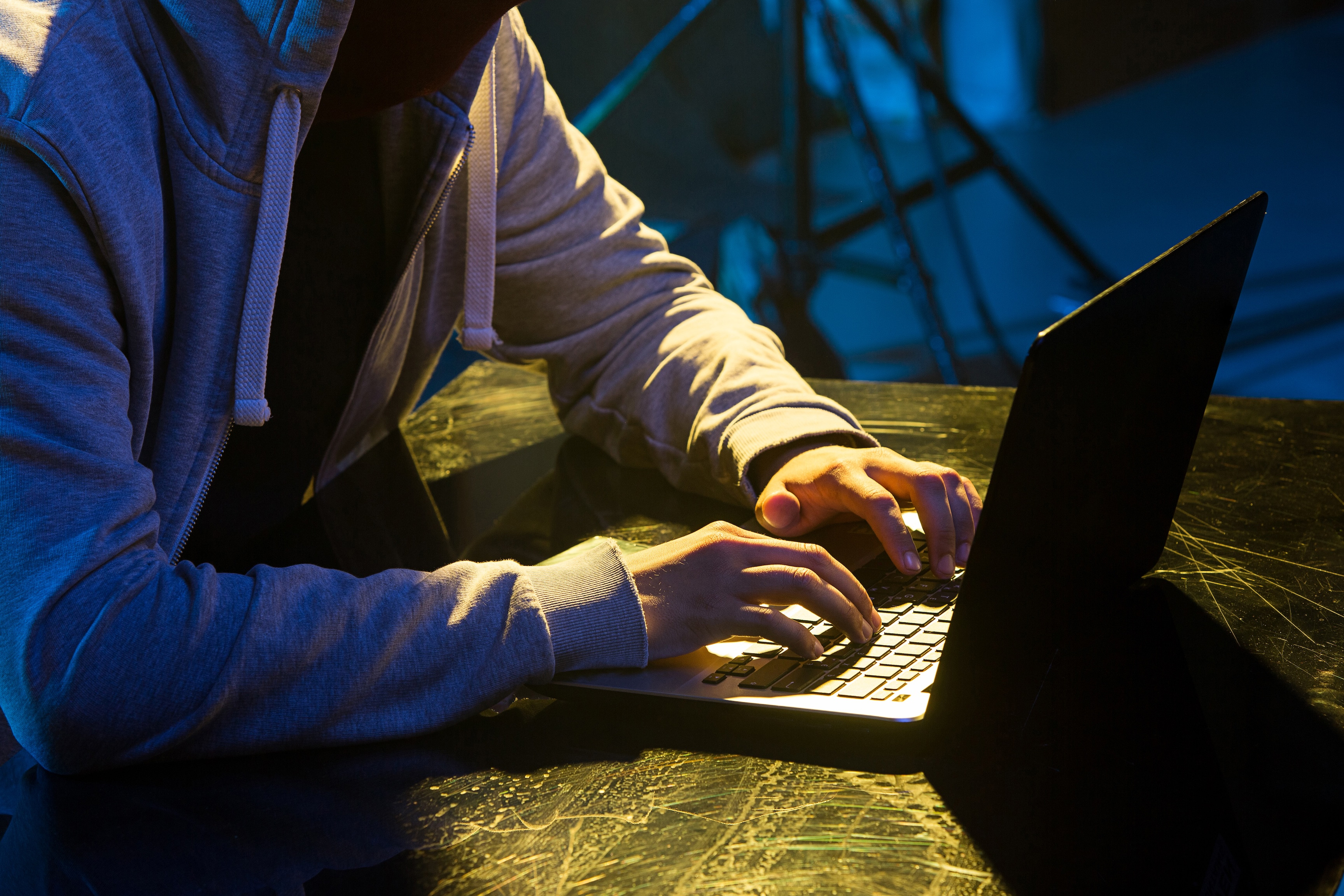 Person mit grauem Kapuzenpulli sitzt am Laptop