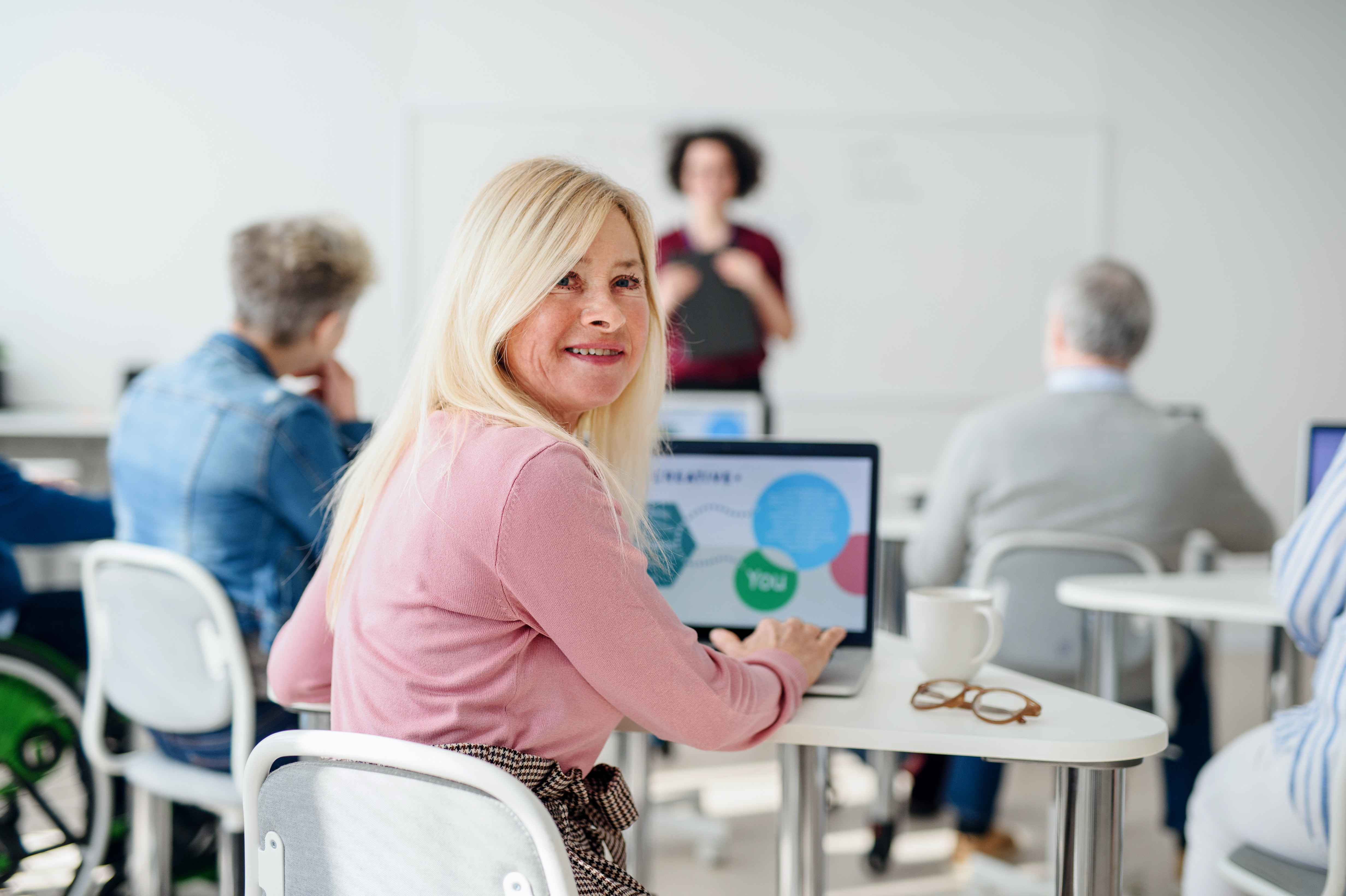 Gruppe von älteren Menschen sitzen in einem Schulzimmer im Unterricht